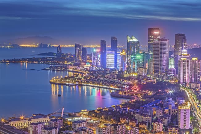 Chongqing after dark — towers stacked up the hillside, their light spilling onto the river