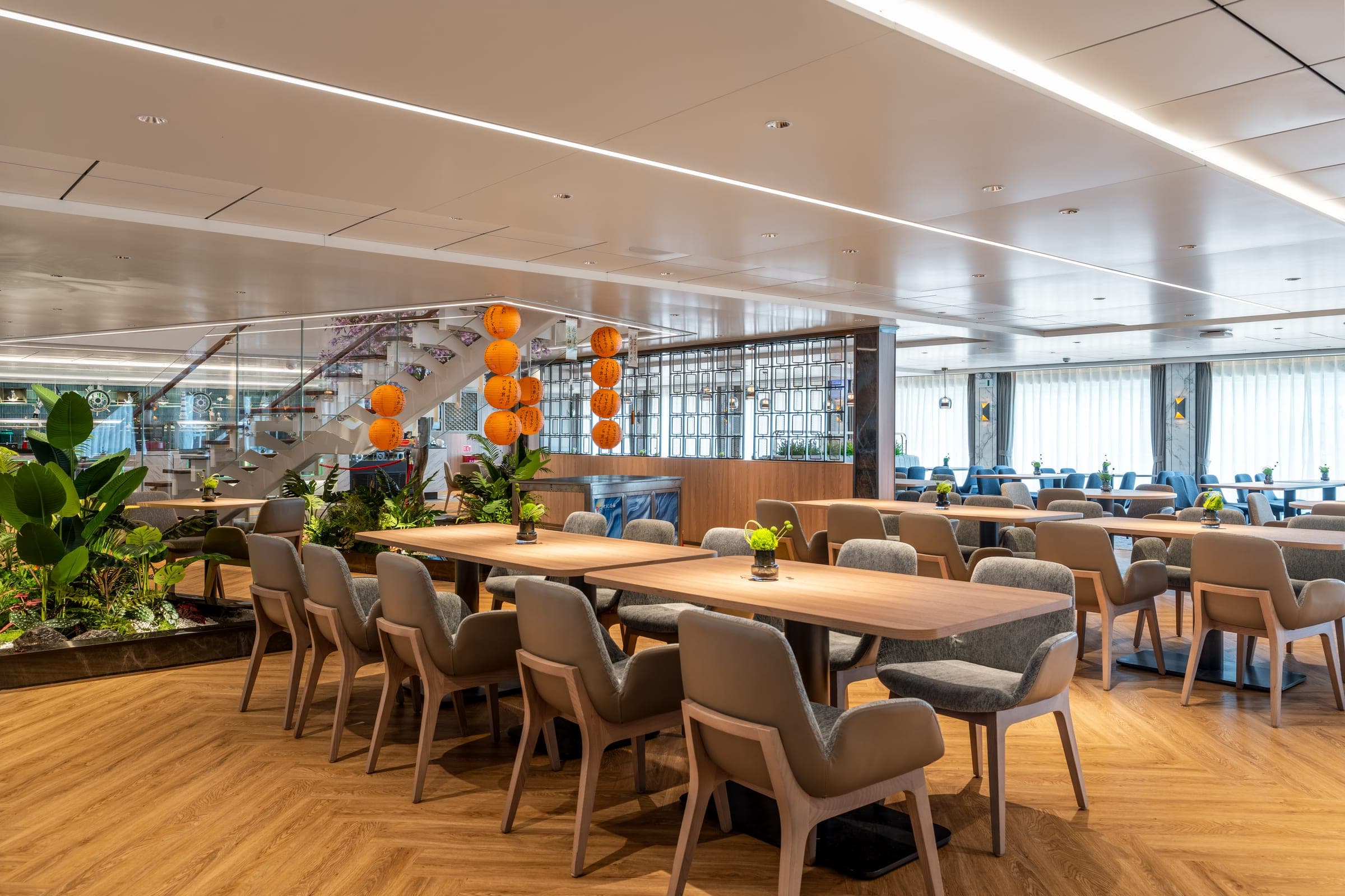 The Globe Dining Room — pale timber tables under a double-height window wall