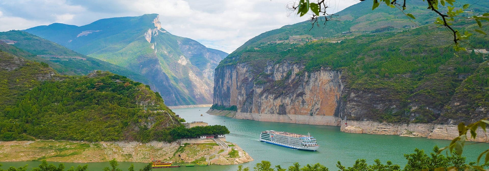 A river cruise vessel below sheer gorge walls, the river turning out of frame