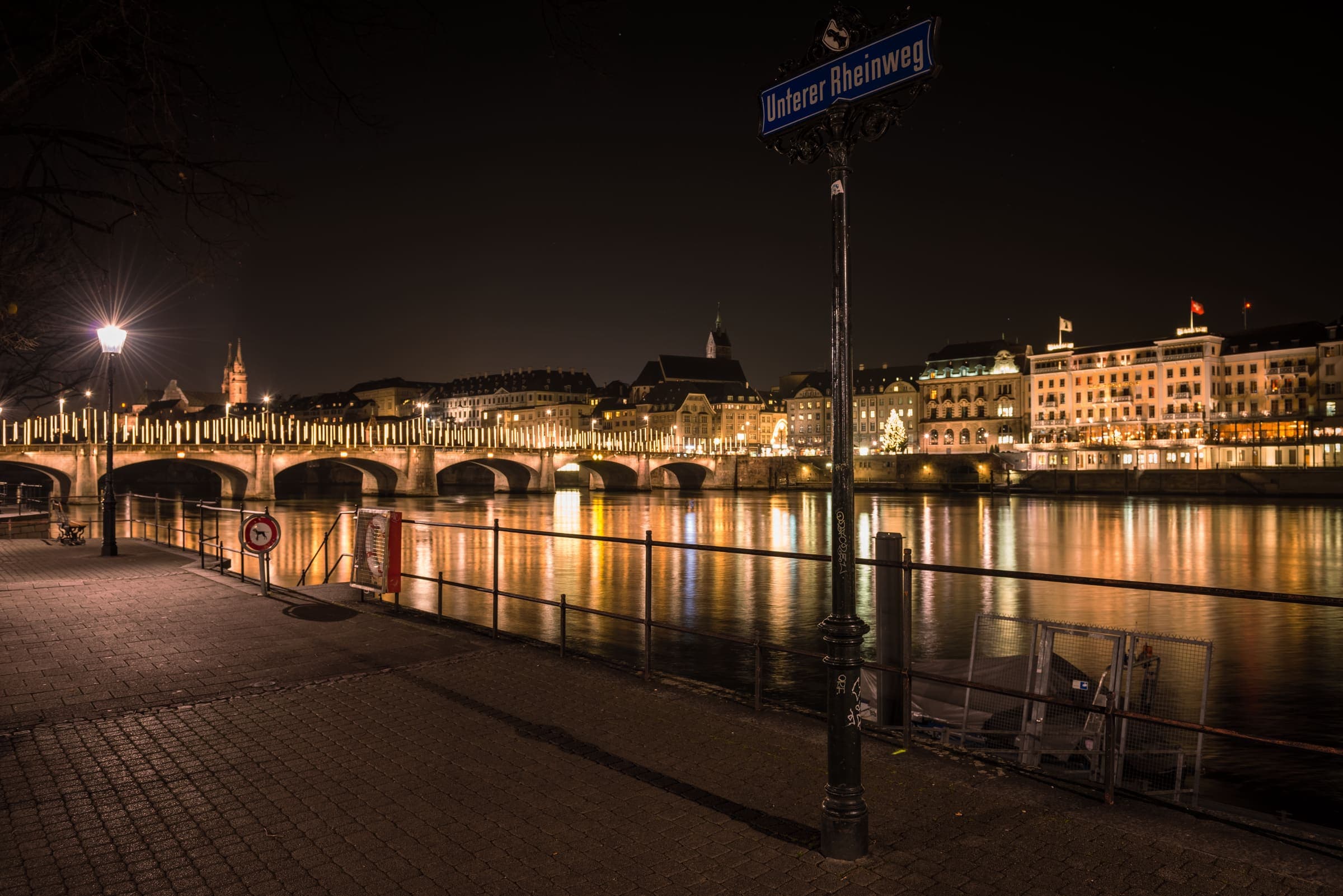 The Rhine at Basel after dark, the lit quayside and bridge reflected in the water