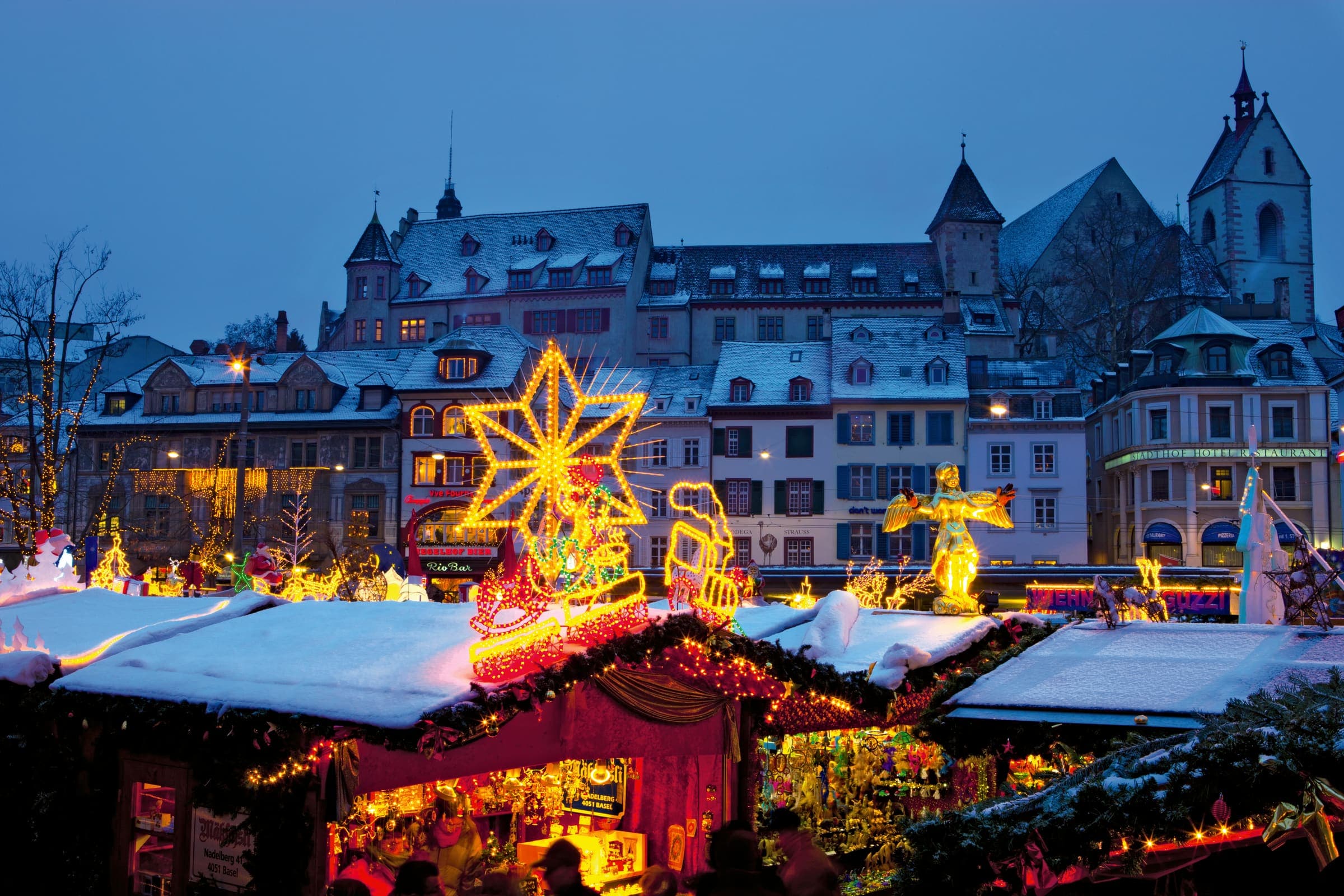 The Basel Christmas market at blue hour, lit stalls beneath the old town gables